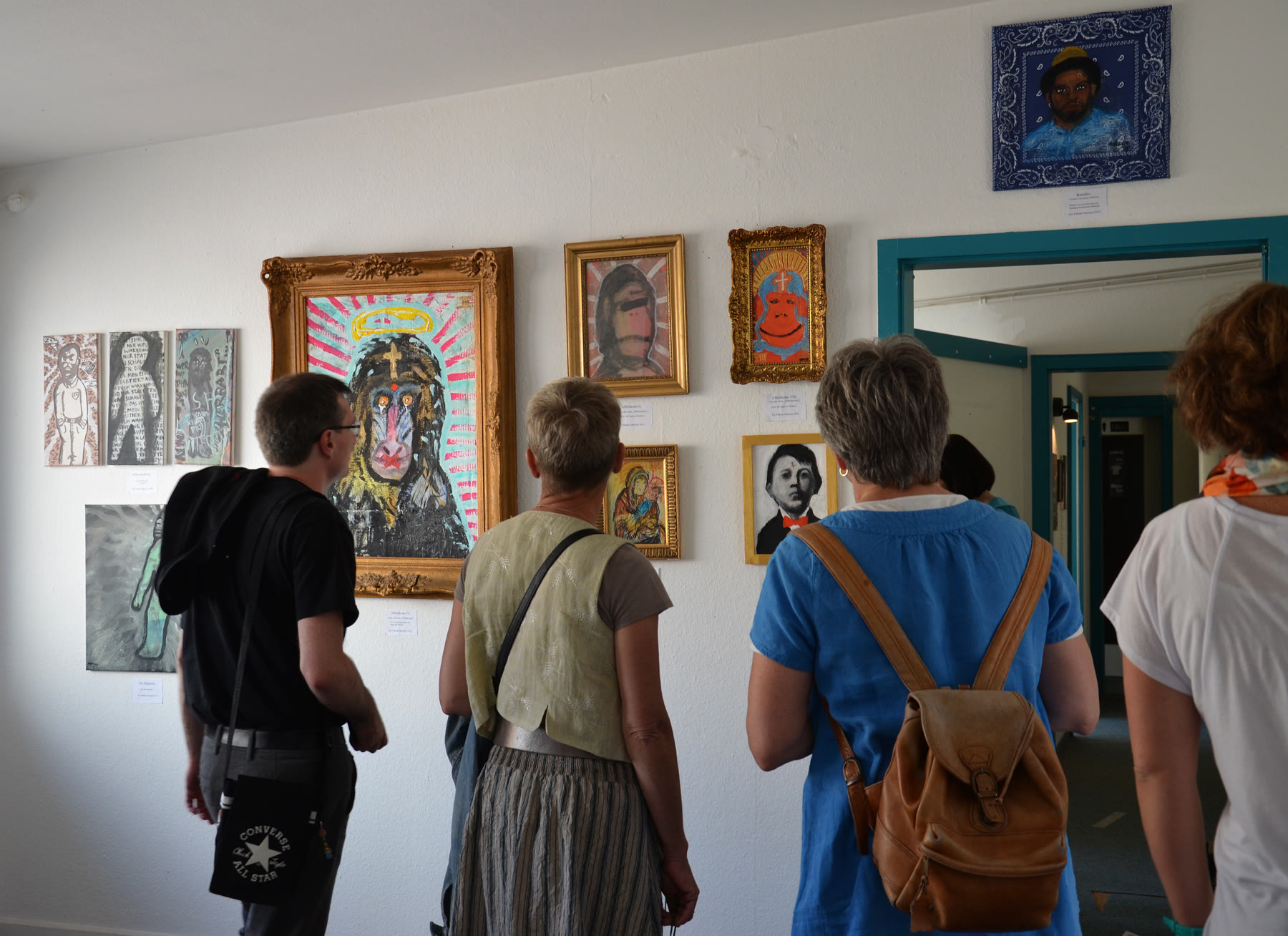 Besucherinnen und Besucher stehen vor einer dicht gehängten Bilderwand
