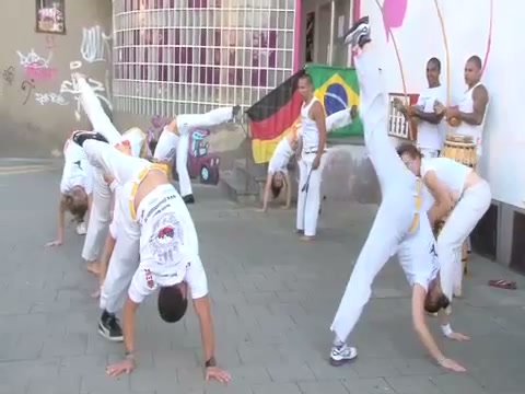 Mehrere Capoeira-Akteure bewegen sich gemeinsam vor der Kulturfahrschule