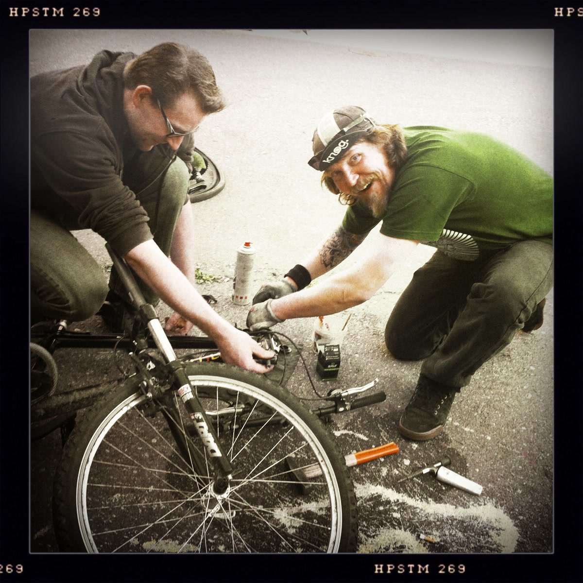 Drei Beteiligte reparieren gemeinsam ein Fahrrad