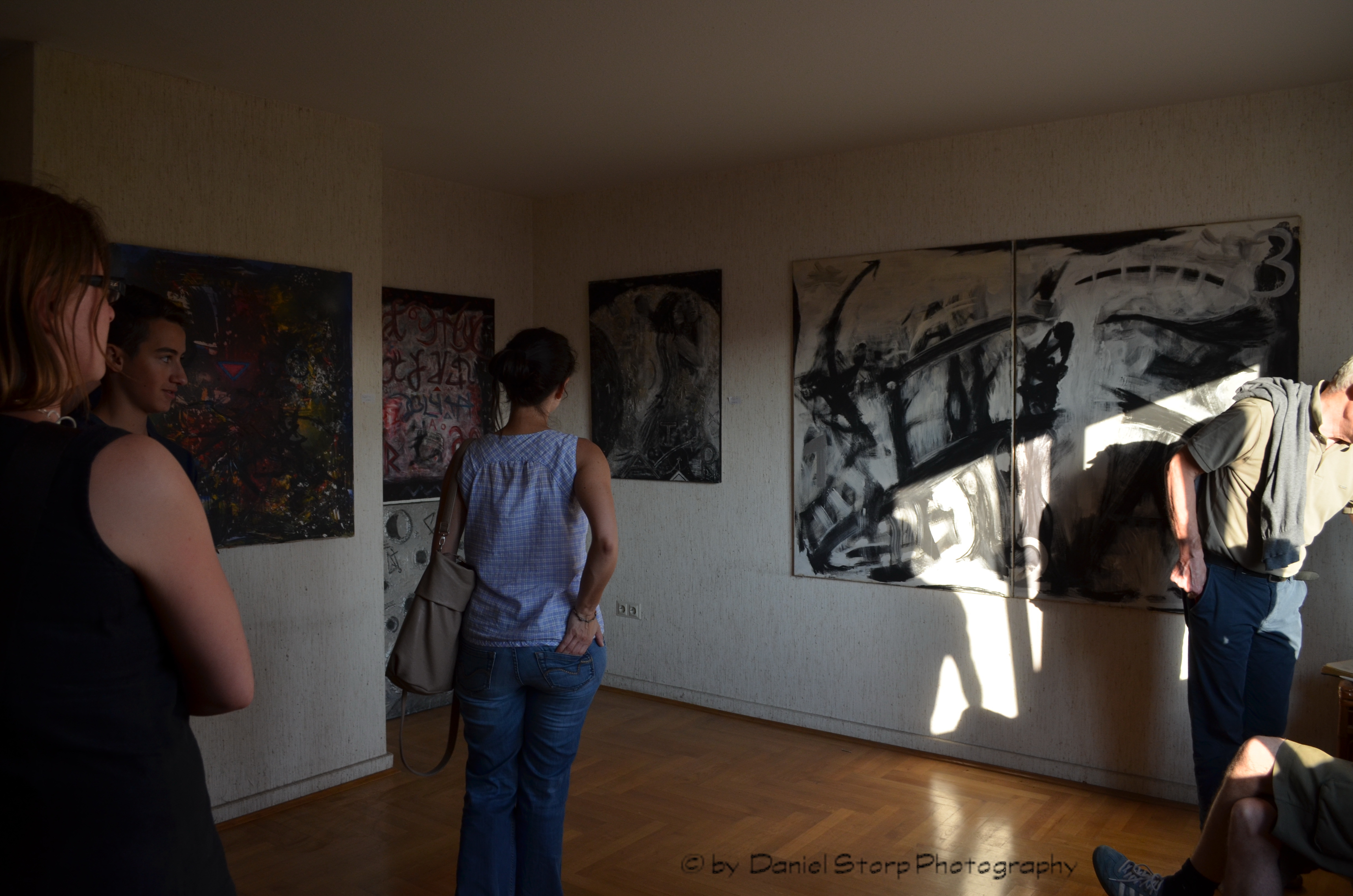Besucher betrachten Arbeiten in einem Ausstellungszimmer