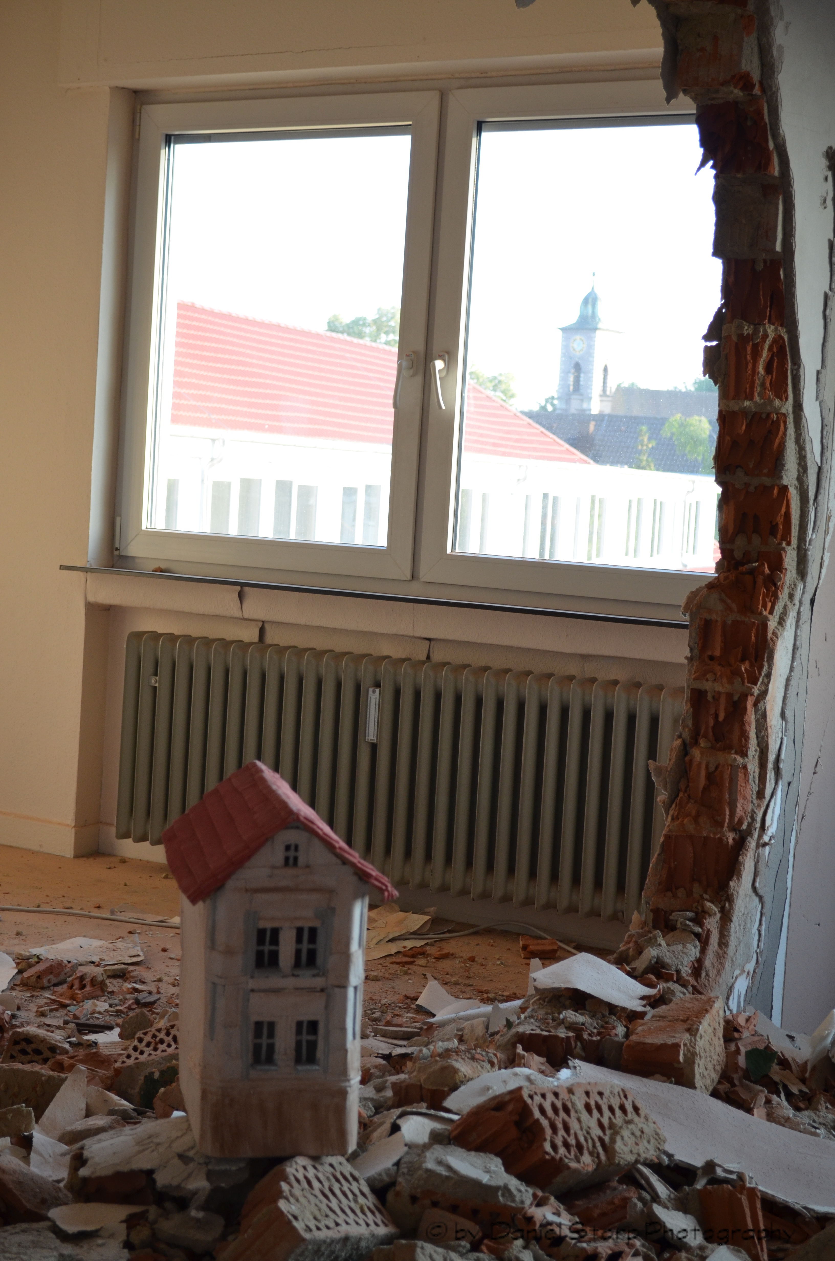Ein kleines Haus steht inmitten einer aufgebrochenen Rauminstallation
